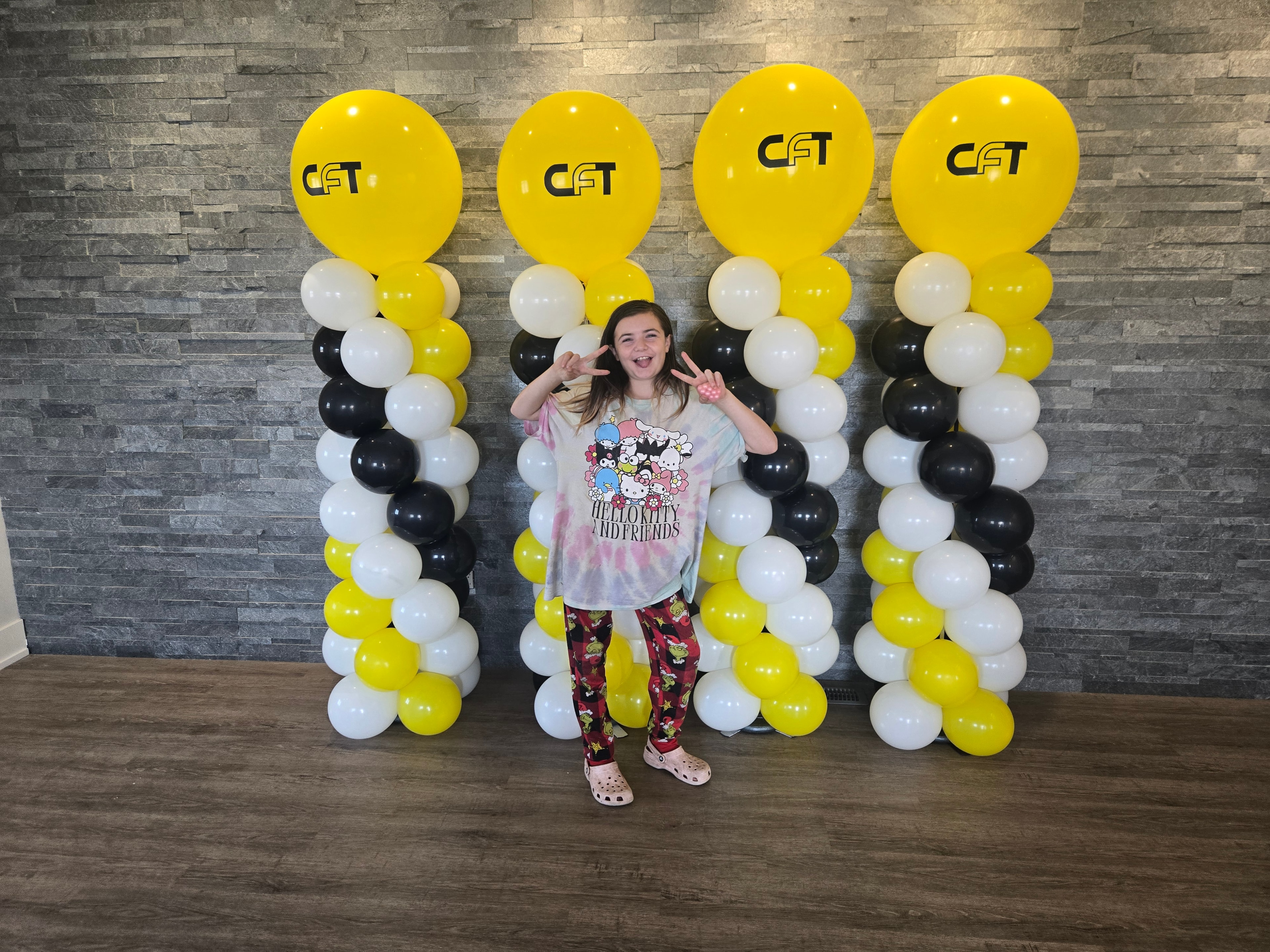 Girl posing in front of CFT branded balloon columns indoors